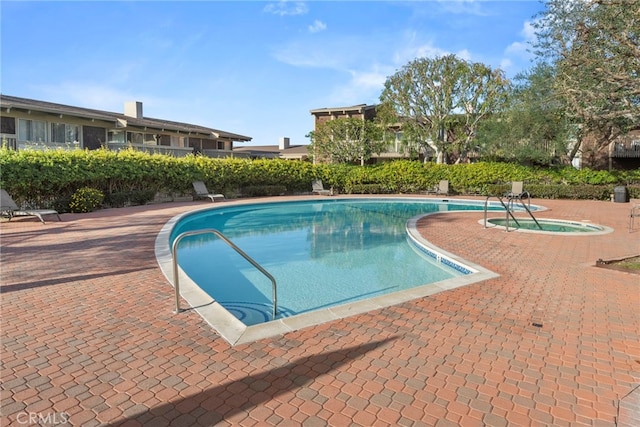 view of swimming pool featuring an in ground hot tub and a patio