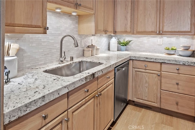 kitchen featuring tasteful backsplash, light stone counters, sink, dishwasher, and light hardwood / wood-style floors