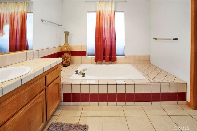 bathroom featuring tile patterned floors, a relaxing tiled tub, and vanity