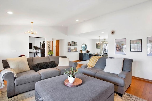 living room with a chandelier, light wood-type flooring, and lofted ceiling