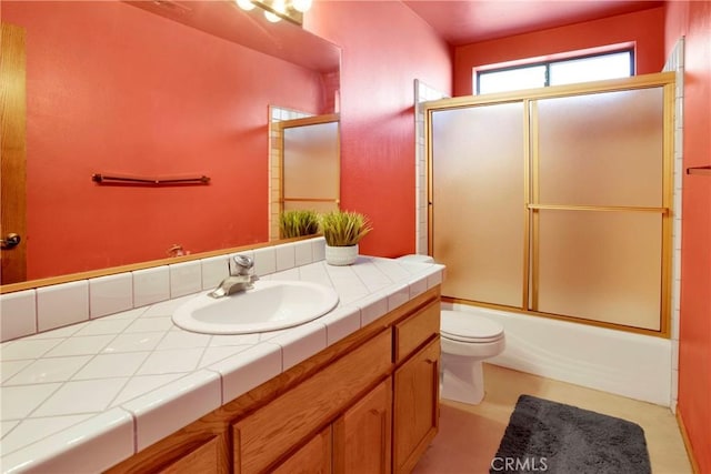 full bathroom featuring vanity, enclosed tub / shower combo, and toilet