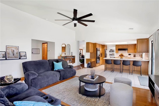 living room featuring ceiling fan, light tile patterned flooring, and high vaulted ceiling