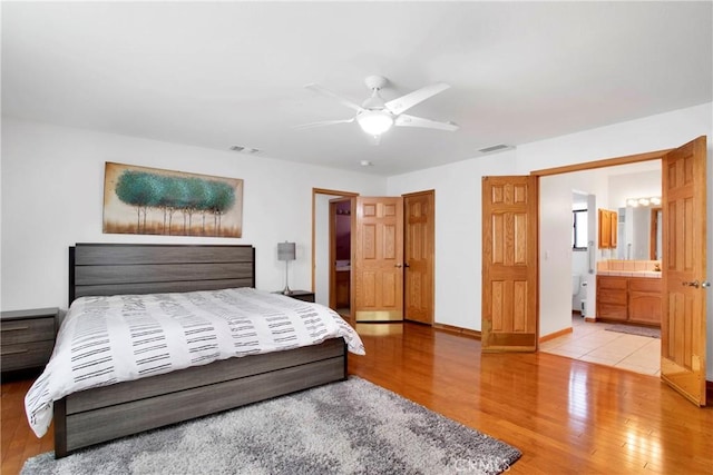 bedroom featuring light hardwood / wood-style flooring, ensuite bath, and ceiling fan