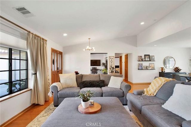 living room with an inviting chandelier, lofted ceiling, and light wood-type flooring