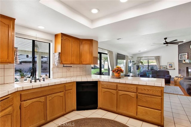 kitchen featuring tile counters, kitchen peninsula, backsplash, and light tile patterned floors