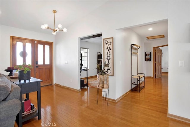 entryway with a chandelier, vaulted ceiling, and hardwood / wood-style flooring