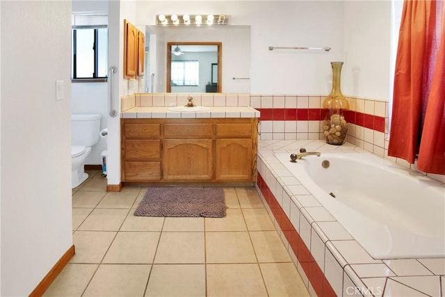 bathroom featuring tile patterned flooring, vanity, toilet, and tiled tub