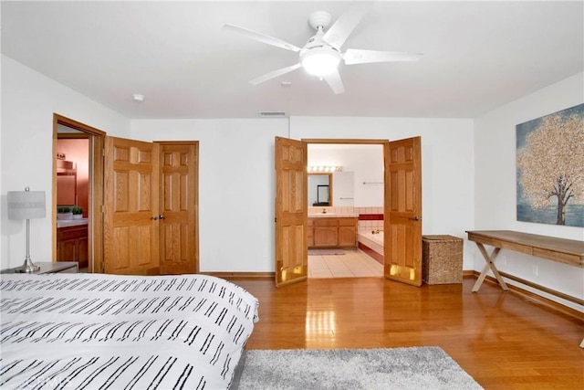 bedroom featuring connected bathroom, ceiling fan, and light wood-type flooring