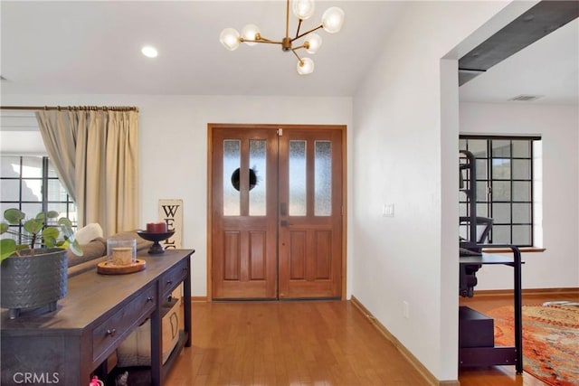 entryway featuring wood-type flooring and a chandelier