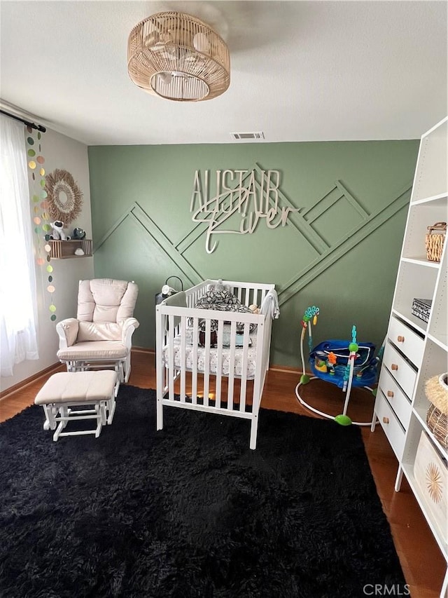 bedroom with a crib and wood-type flooring