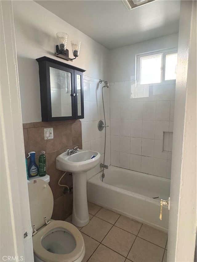 bathroom featuring tile patterned flooring, tiled shower / bath combo, tile walls, and toilet