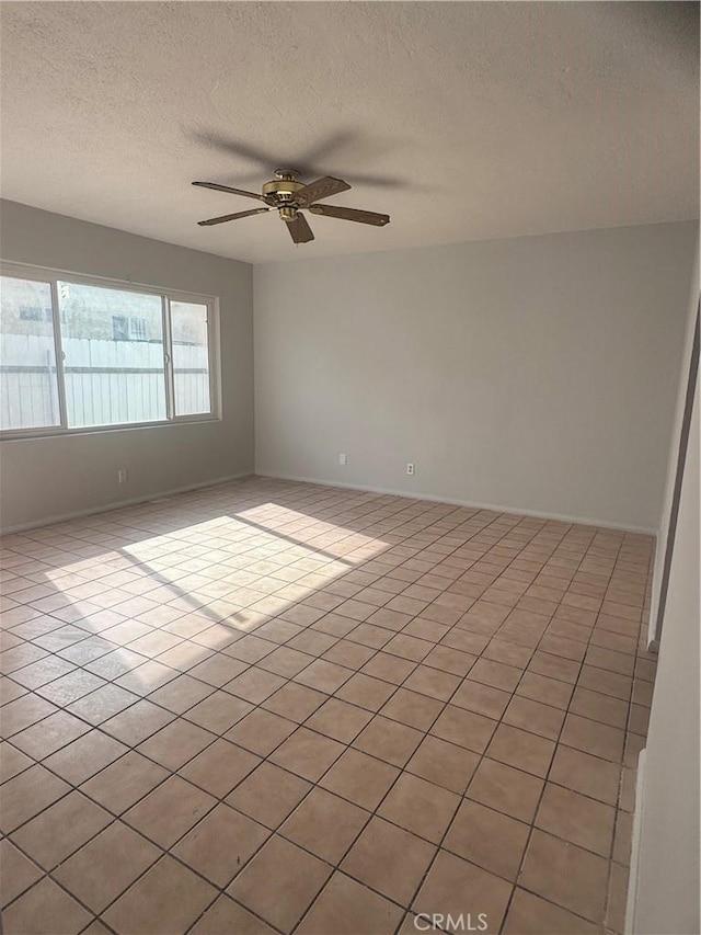 tiled spare room with a textured ceiling and ceiling fan