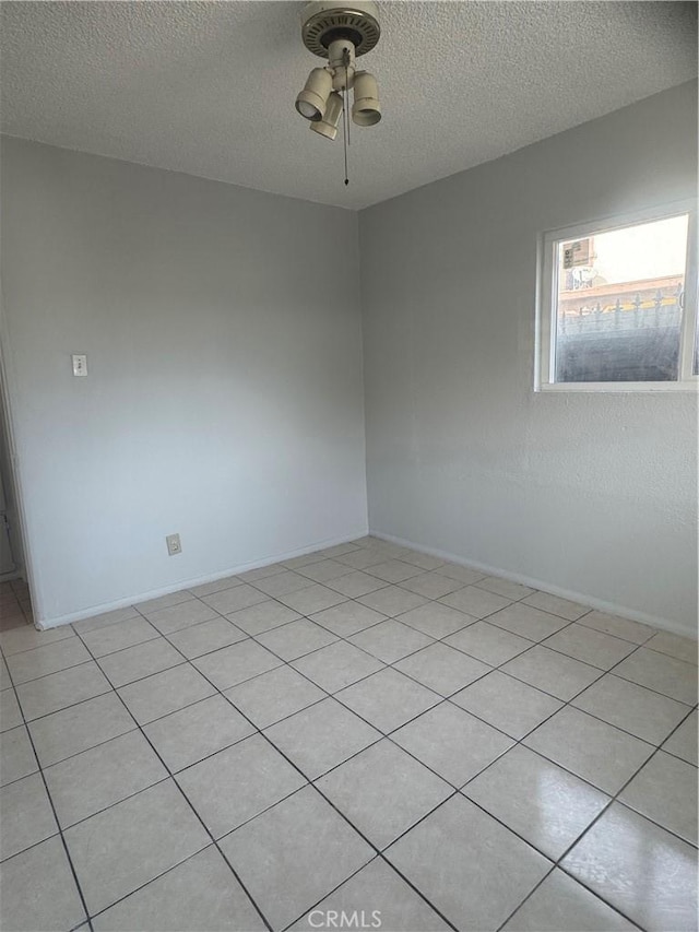 spare room with ceiling fan, light tile patterned floors, and a textured ceiling