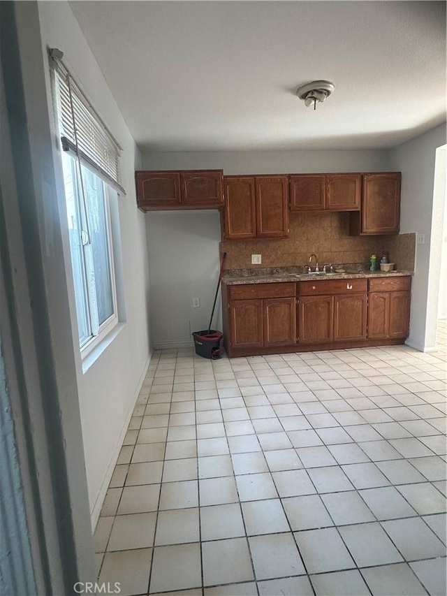 kitchen with tasteful backsplash, light tile patterned floors, and sink