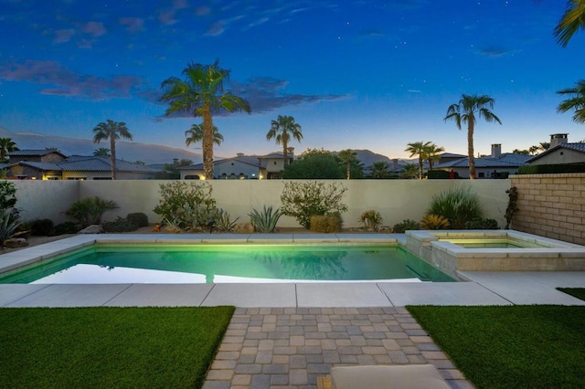 pool at dusk featuring a mountain view and an in ground hot tub