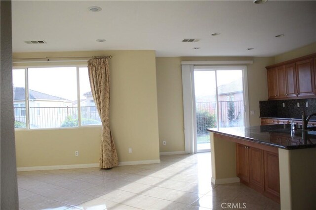 kitchen with light tile patterned floors, a healthy amount of sunlight, and tasteful backsplash