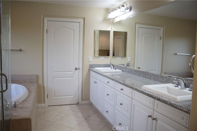 bathroom with tiled bath, vanity, and tile patterned flooring