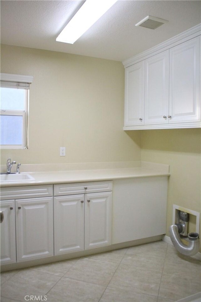 laundry room with cabinets, light tile patterned floors, and sink