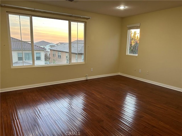 spare room with a healthy amount of sunlight and dark wood-type flooring