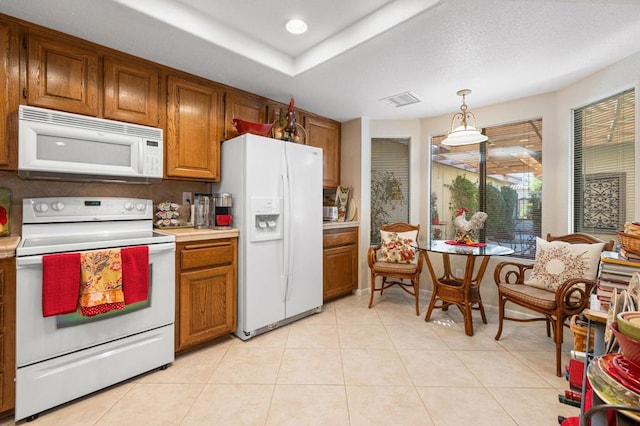 kitchen with white appliances, hanging light fixtures, and light tile patterned floors