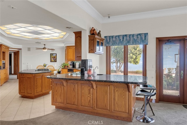 kitchen with light carpet, kitchen peninsula, ceiling fan, and ornamental molding