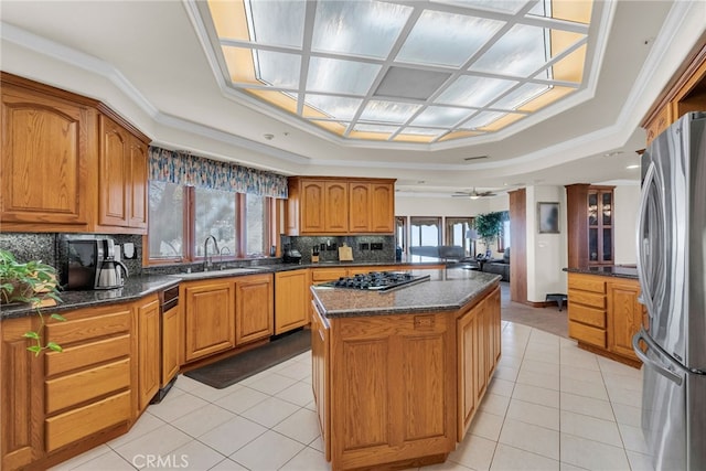 kitchen with a center island, sink, light tile patterned floors, ornamental molding, and appliances with stainless steel finishes