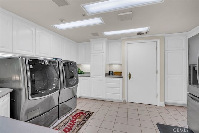 washroom with cabinets, light tile patterned floors, and washer and dryer