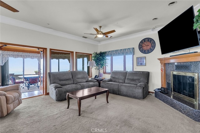 living room featuring carpet flooring, ceiling fan, ornamental molding, and a premium fireplace