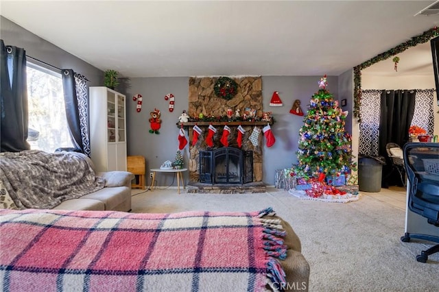 carpeted living room with a stone fireplace