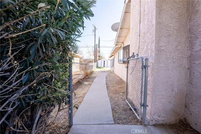 view of side of home featuring fence, a gate, and stucco siding