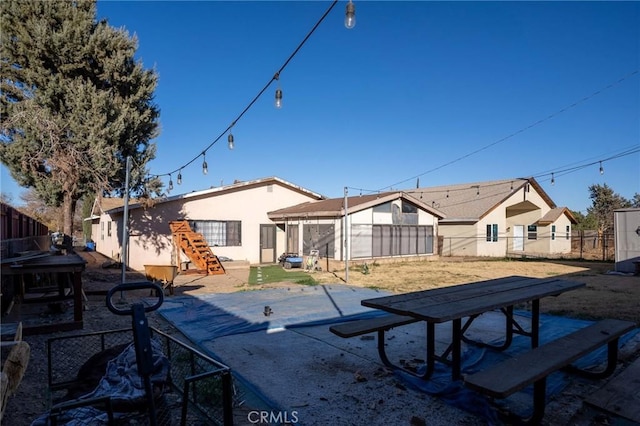 rear view of house featuring a patio area, fence, and stucco siding