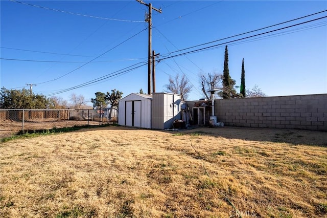 view of yard with an outbuilding, a shed, and a fenced backyard