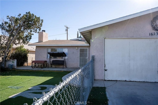 view of home's exterior featuring a patio, fence, a lawn, stucco siding, and a chimney