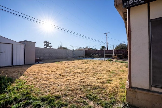 view of yard with a fenced backyard, a storage unit, and an outdoor structure