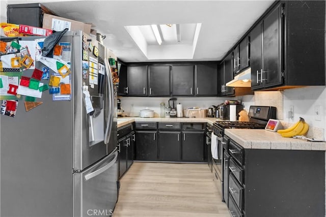 kitchen with light countertops, appliances with stainless steel finishes, dark cabinetry, and under cabinet range hood