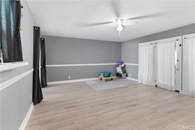 recreation room with light wood finished floors, baseboards, and a ceiling fan