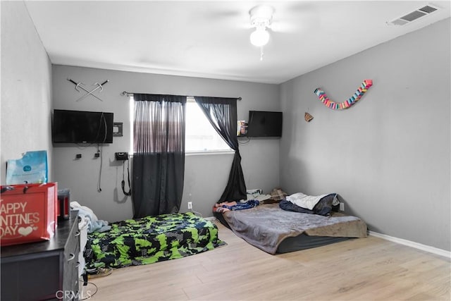 bedroom with baseboards, visible vents, and wood finished floors