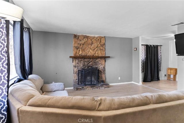 living area with light wood-type flooring, visible vents, a fireplace, and baseboards