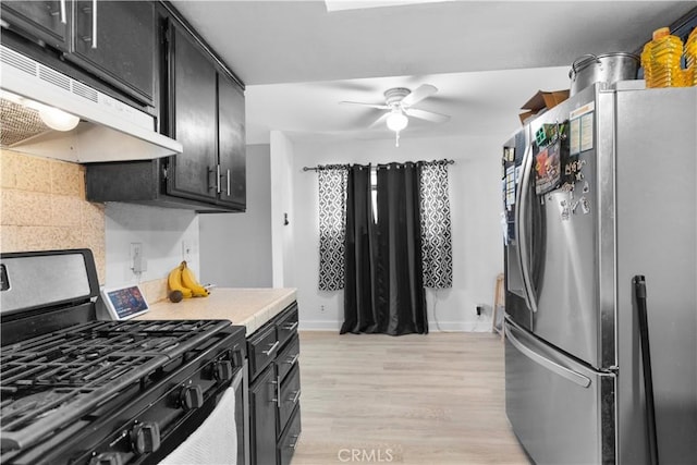 kitchen featuring range with gas cooktop, light countertops, dark cabinets, under cabinet range hood, and stainless steel fridge with ice dispenser