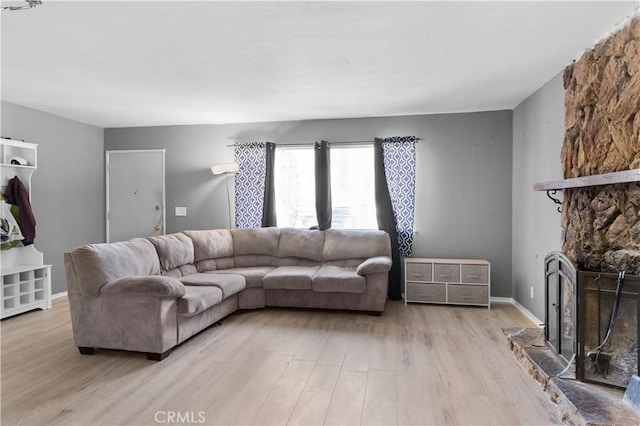 living room featuring light wood-type flooring, a fireplace, and baseboards