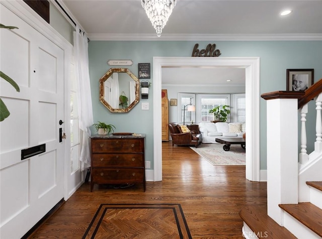 entrance foyer featuring dark wood-type flooring, crown molding, and an inviting chandelier