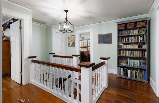 hallway with ornamental molding, dark wood-type flooring, and an inviting chandelier