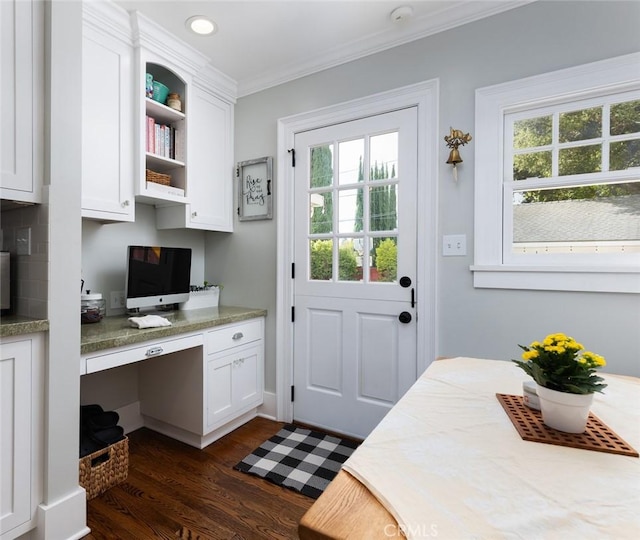 office space with dark hardwood / wood-style flooring, built in desk, and ornamental molding