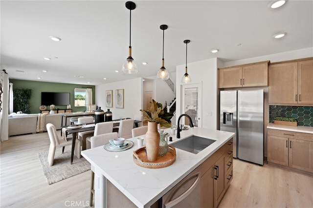 kitchen with stainless steel appliances, light hardwood / wood-style flooring, a kitchen island with sink, and sink