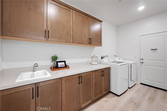 washroom featuring cabinets, washing machine and dryer, light hardwood / wood-style floors, and sink