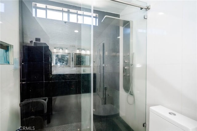 bathroom featuring a shower with shower door and toilet