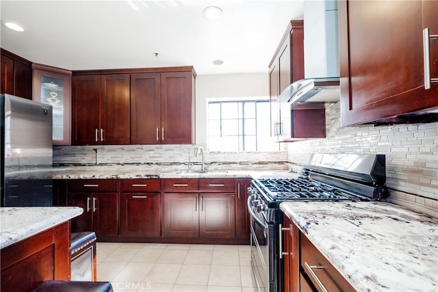 kitchen with stainless steel appliances, light stone counters, tasteful backsplash, and wall chimney exhaust hood