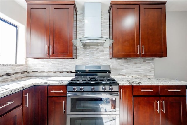 kitchen with tasteful backsplash, light stone counters, high end stainless steel range, and wall chimney range hood