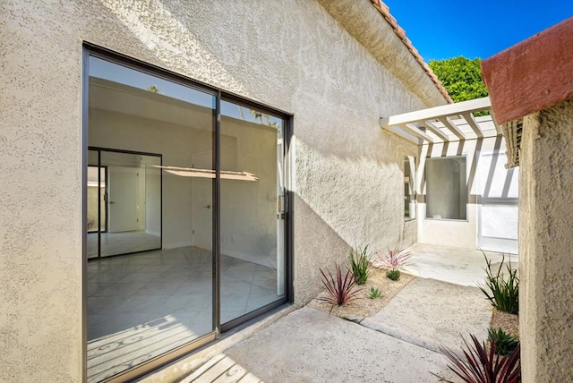 view of exterior entry featuring a pergola and a patio