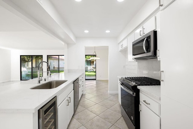 kitchen featuring sink, hanging light fixtures, stainless steel appliances, beverage cooler, and white cabinets